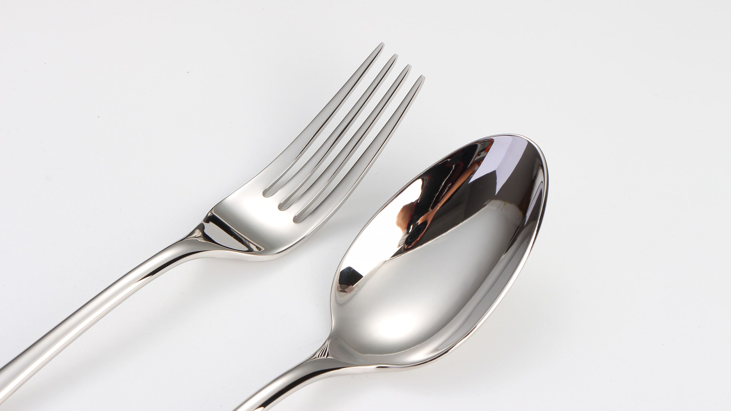A side-by-side comparison of a machine-polished spoon and a hand-polished spoon, highlighting the difference in reflection clarity.